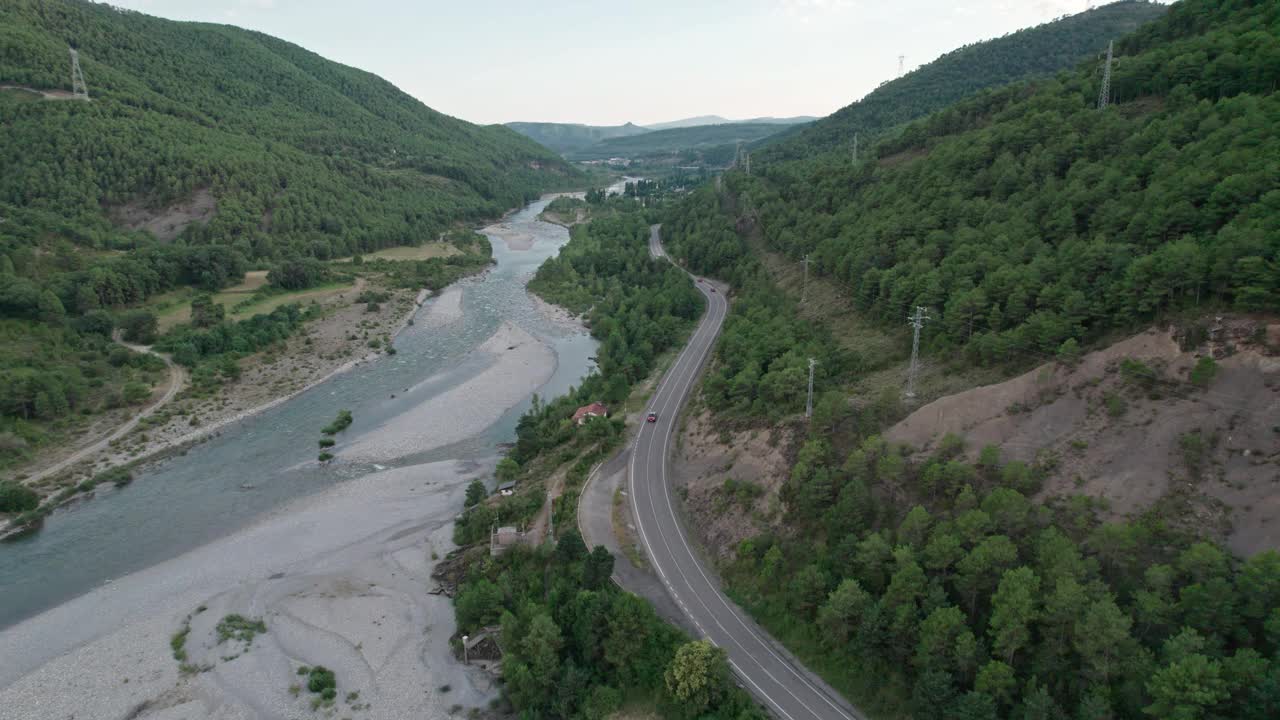 山河沿路而下的俯视图。河流和道路并行运输，绿色森林和岩石海岸。视频素材