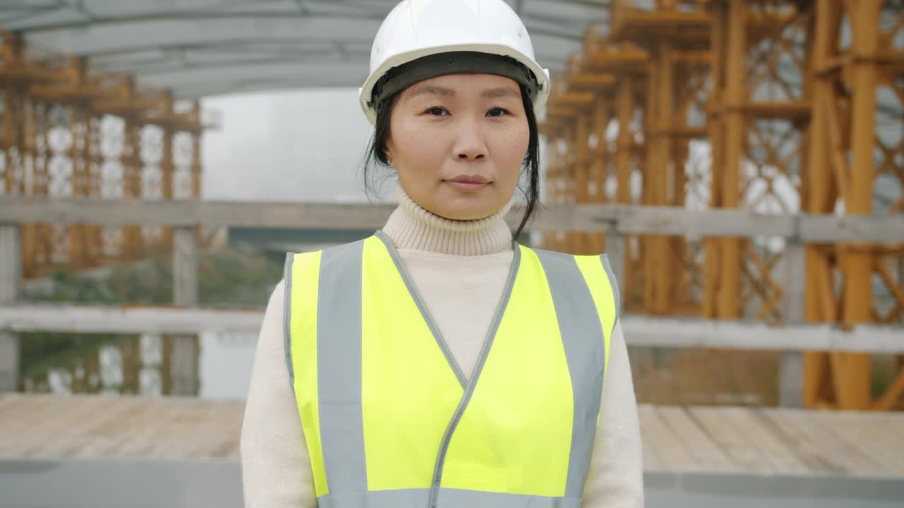 女建筑工人戴着安全帽站在工地外的慢动作肖像视频素材