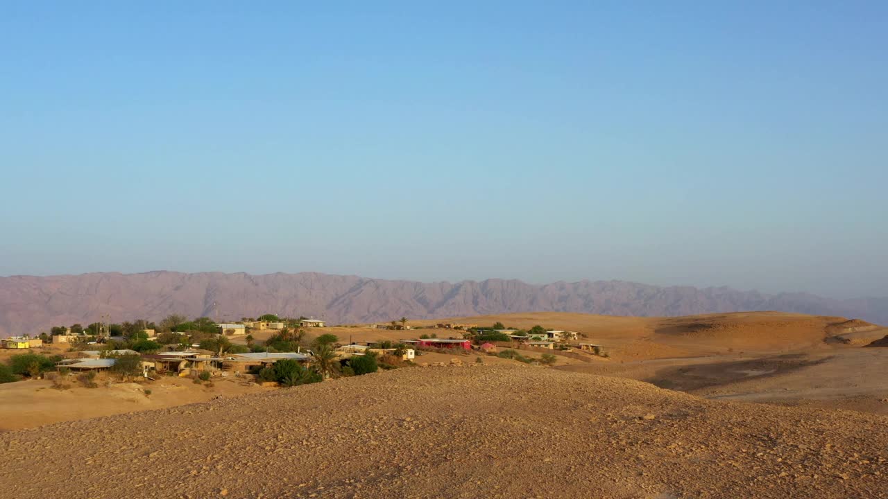 在沙漠山上的建筑的空中风景拍摄，无人机向后飞行的人站在度假- Shaharut，以色列视频素材