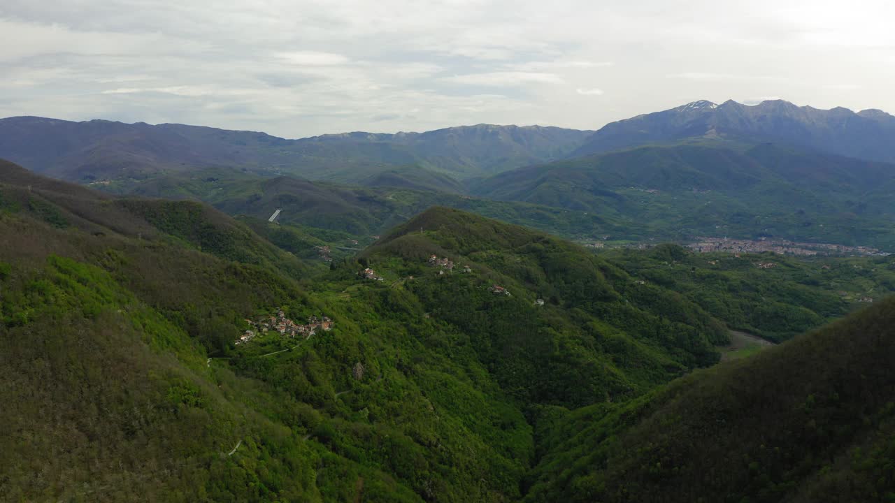 空中向前风景拍摄的房子在绿色的山对多云的天空-亚平宁山脉，意大利视频素材