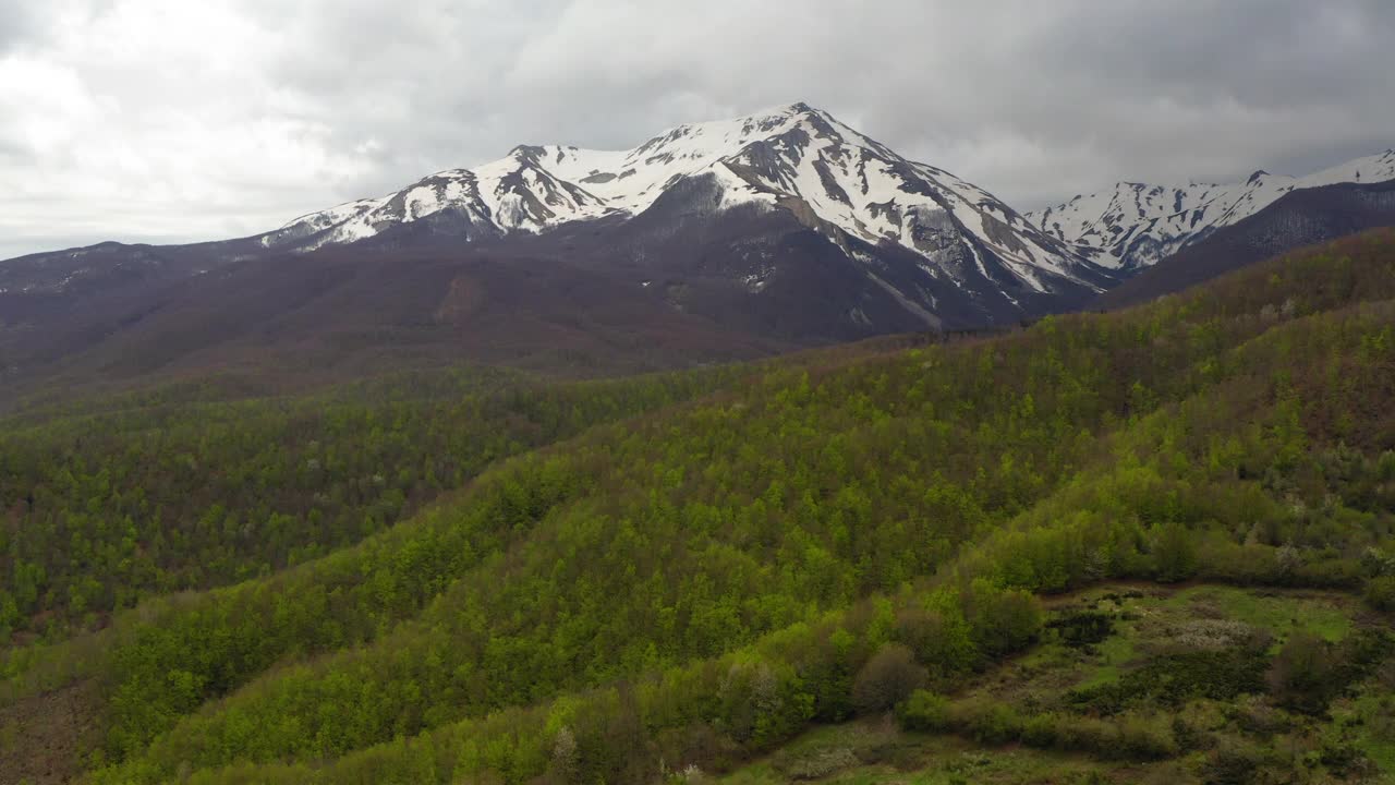 空中积雪覆盖的天然岩层，无人机向前飞行在绿色景观-亚平宁山脉，意大利视频素材