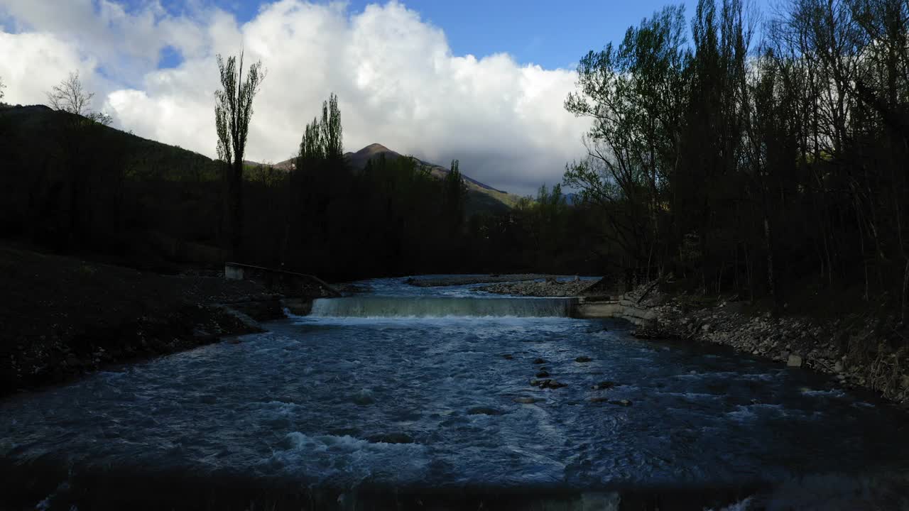 航拍:在多云的天空下自然山丘的风景拍摄，无人机在河水上飞行前进-亚平宁山脉，意大利视频素材