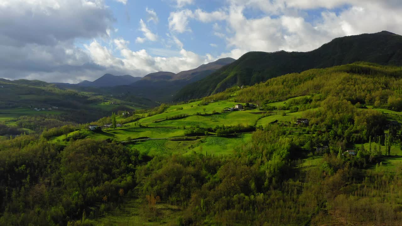 空中前进美丽的房子在绿色的小山景观对多云的天空-亚平宁山脉，意大利视频素材