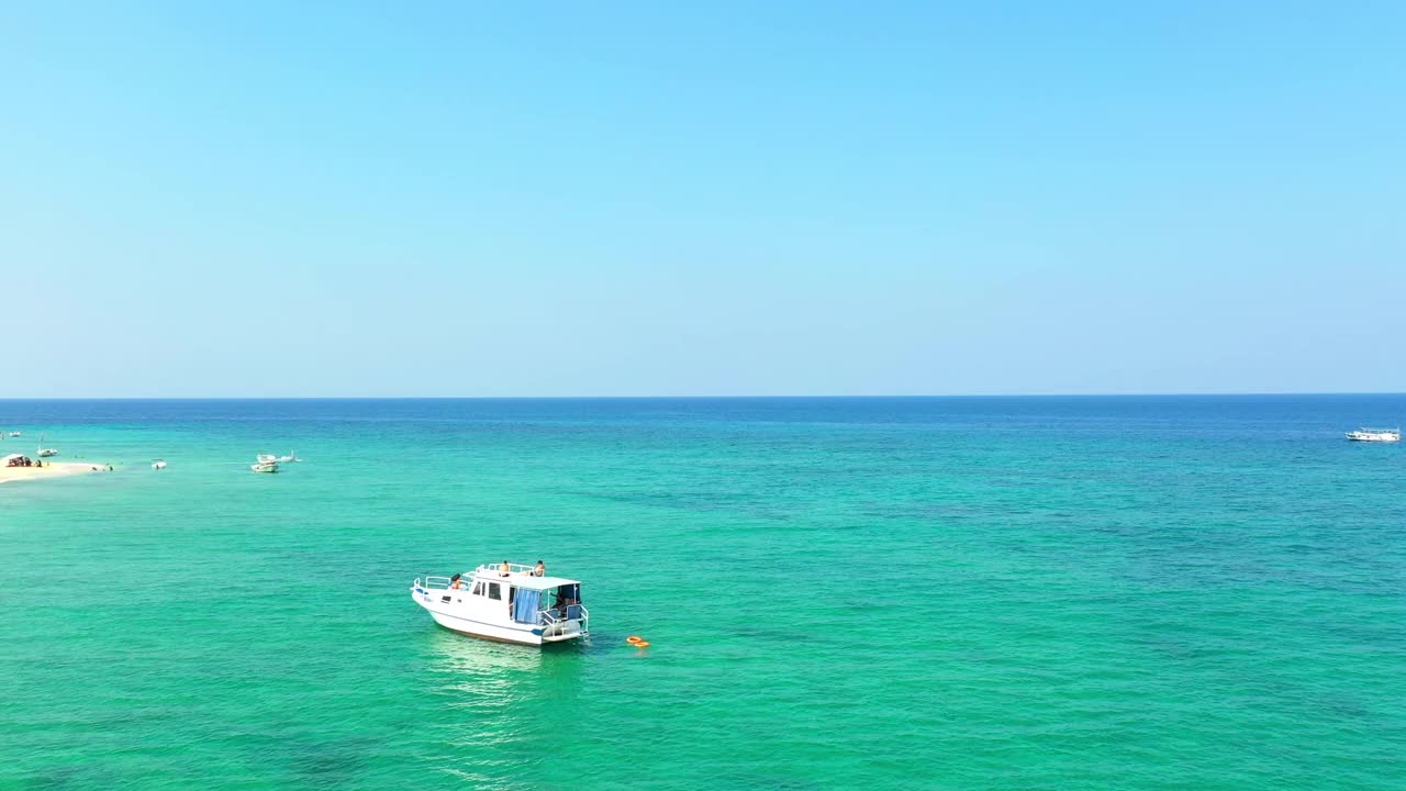 空中摇摄绿松石海上的小船，人们在阳光明媚的日子里探索棕榈岛海滩——黎巴嫩的的黎波里视频素材