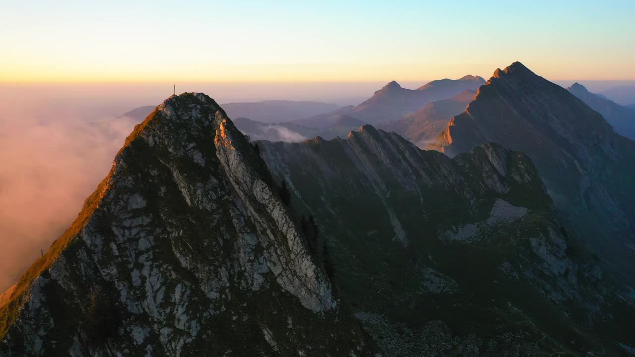 空中平移风景拍摄的宗教符号在山顶，无人机飞越云层在日落期间-科摩因角，瑞士视频素材