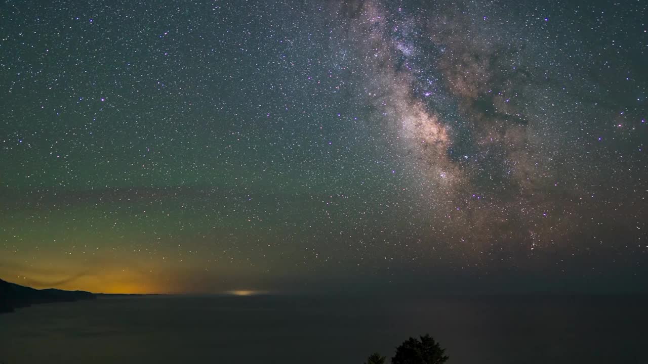 时间推移平移拍摄美丽的银河在海上与照明山在夜间-避难所湾，加利福尼亚视频素材