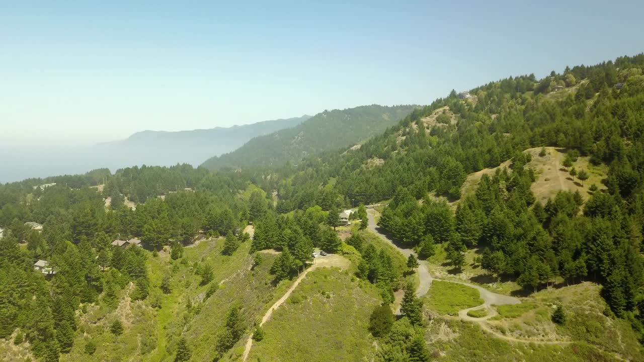 空中拍摄的山脉在晴朗的日子，无人机下降在绿色的树木在森林-北加州，加州视频素材