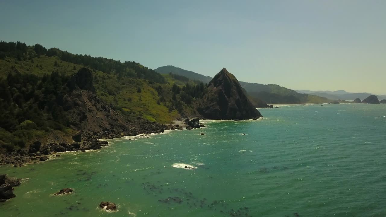 航拍拍摄的海浪冲击海岸线反对蓝天，无人机在阳光明媚的日子飞越海洋-俄勒冈海岸，俄勒冈视频素材