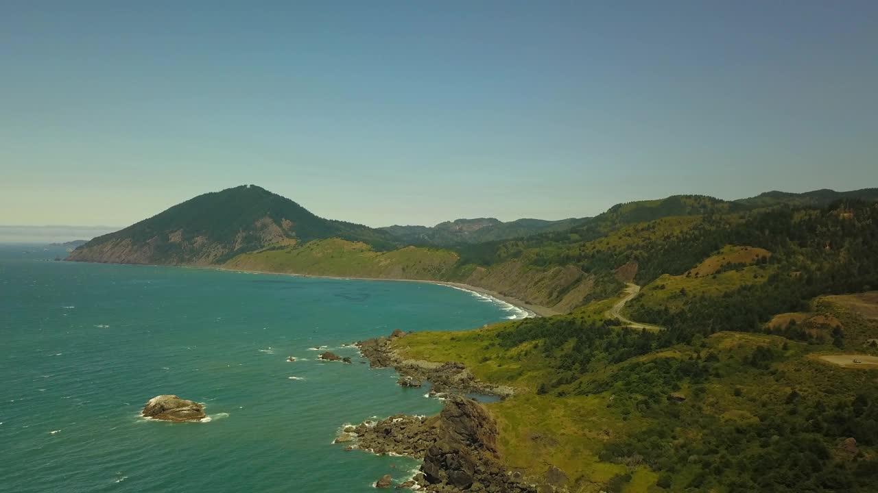 航拍拍摄的海浪冲击海岸线在阳光明媚的日子，无人机飞越大海反对蓝天-俄勒冈海岸，俄勒冈视频素材