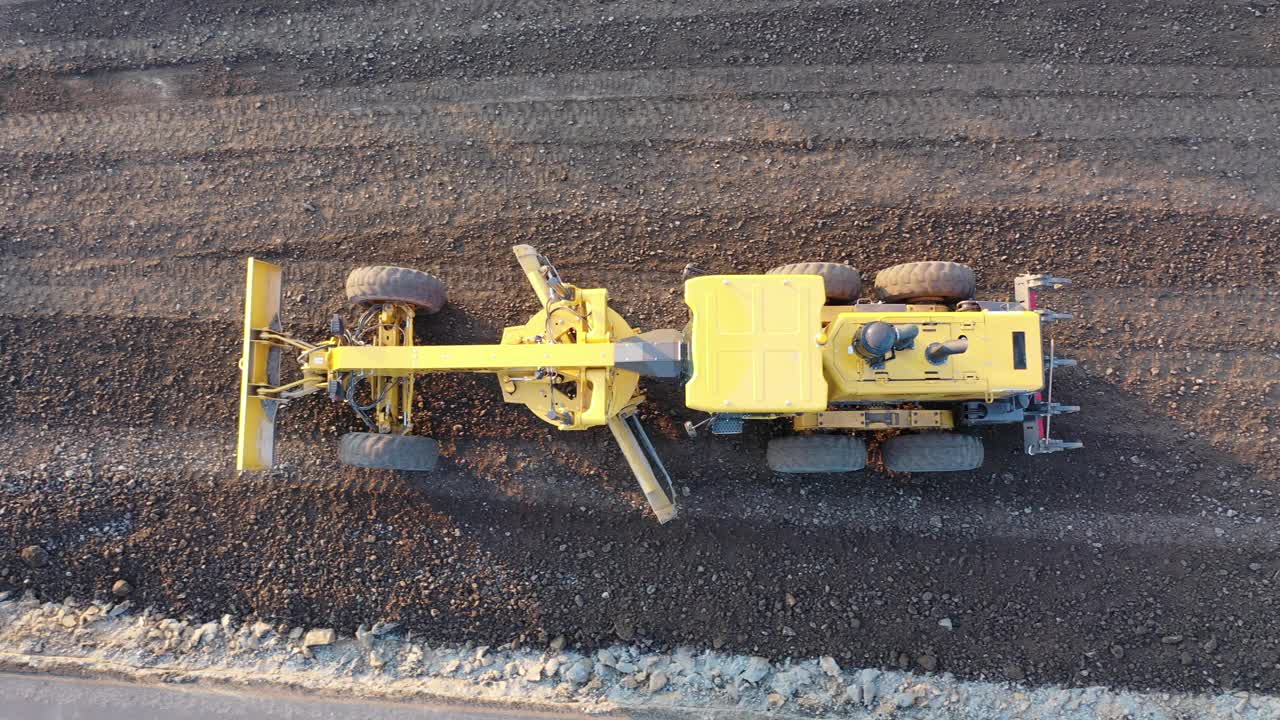 平地机道路建设工业机械建设的新道路。在砂土路面基础平整过程中，机动平地机的叶片。平地工正在筑路。视频素材