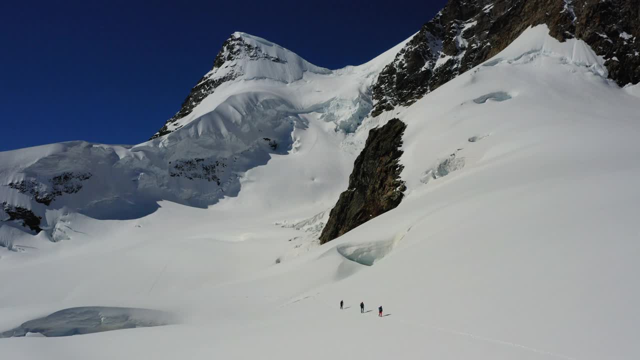 空中拍摄的人行走在雪山景观在晴朗的天空- Lauterbrunnen，瑞士视频素材