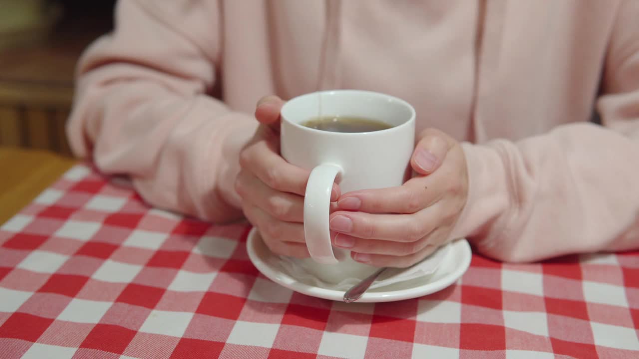 冻僵的女人温暖她的手，手指在一杯白色的茶上移动视频素材