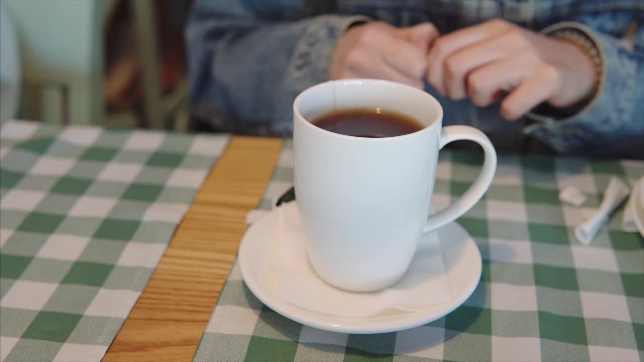 特写镜头，一个女孩正在往一杯红茶里倒糖棒视频素材