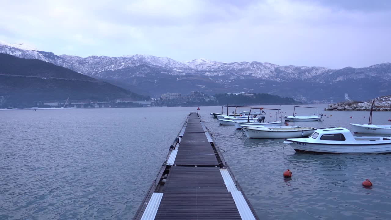 布德瓦的码头上停泊着船只，背景是积雪覆盖的山脉视频素材