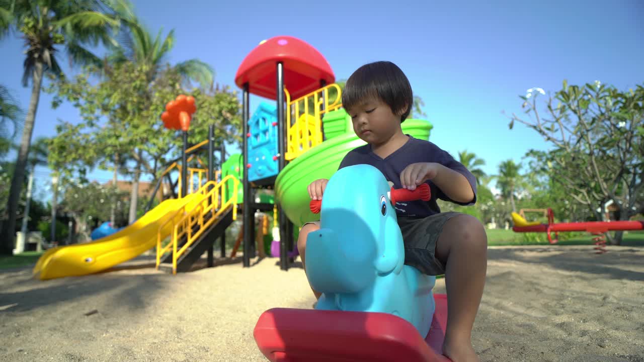 小男孩在操场上骑着大象玩具视频素材