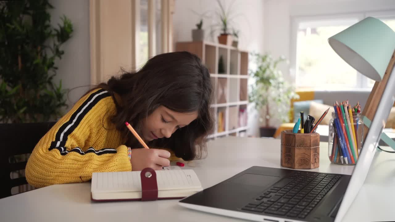 可爱的白人小学女学生做她的家庭作业，同时使用了大量的技术视频素材