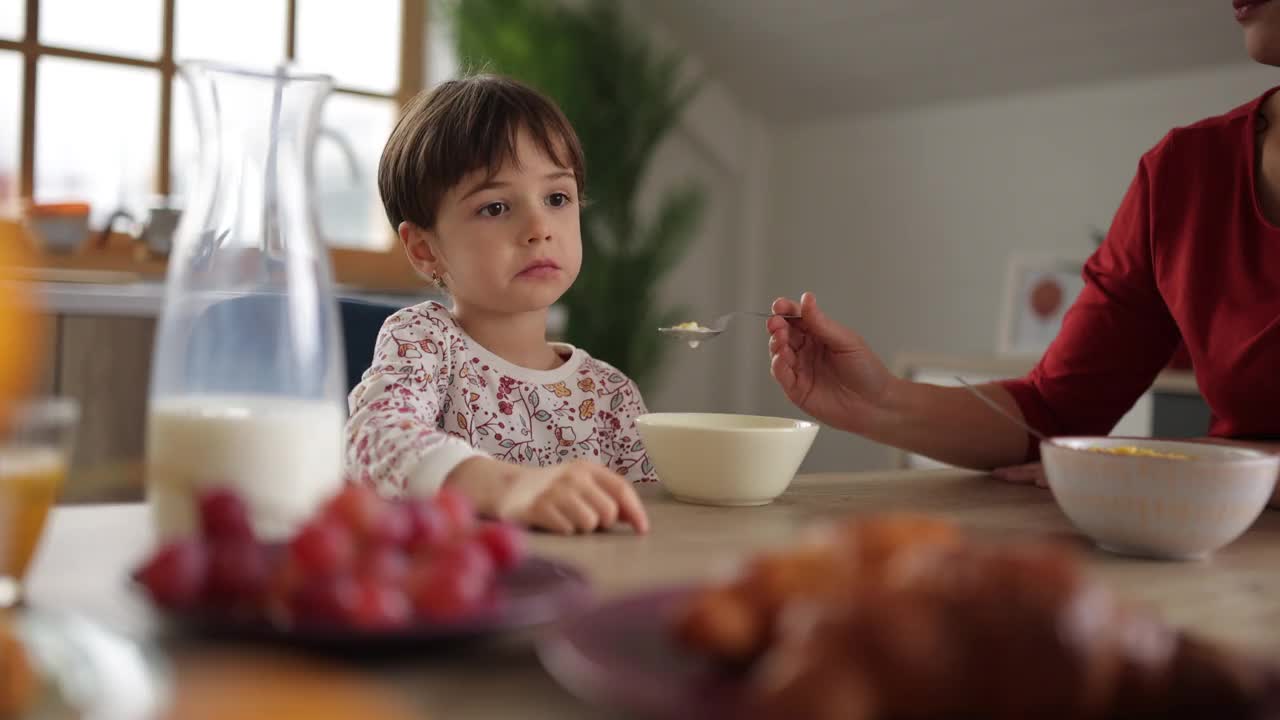 妈妈在家里的餐厅用麦片给她的小女儿吃早餐视频素材