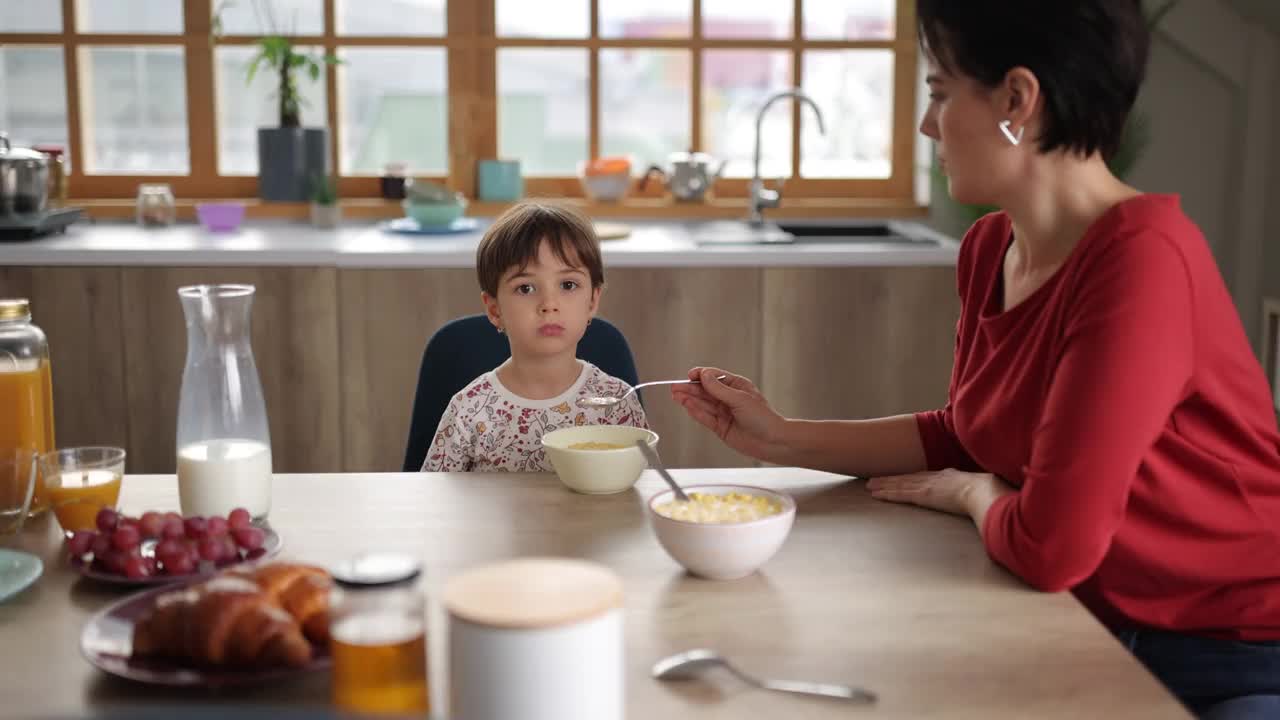 妈妈在家里的餐厅用麦片给她的小女儿吃早餐视频素材