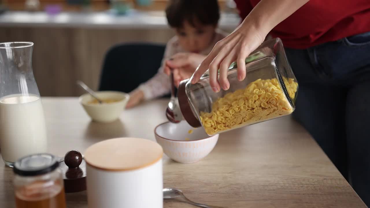 妈妈在家里的餐厅为她的小女儿准备早餐视频素材