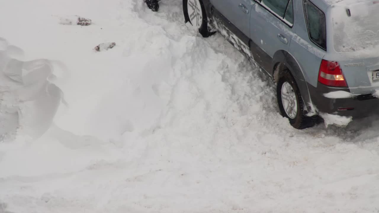 一辆乘用车在院子里踩着冬胎在雪地里打滑。光滑的表面下有雪，冰，车轮旋转视频素材