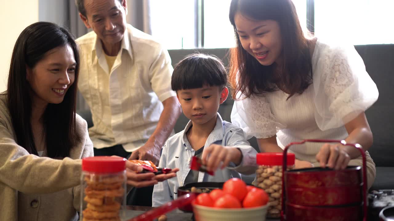 小男孩帮助他的母亲把零食放进糖果盒庆祝中国新年视频素材