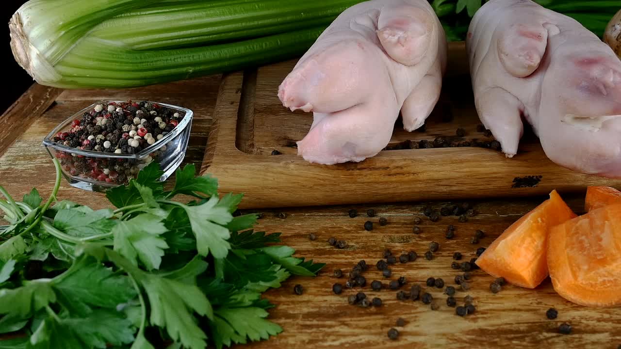 生猪肉腿，不同的蔬菜和香料准备美味的高汤或肉冻木制厨房板。视频素材