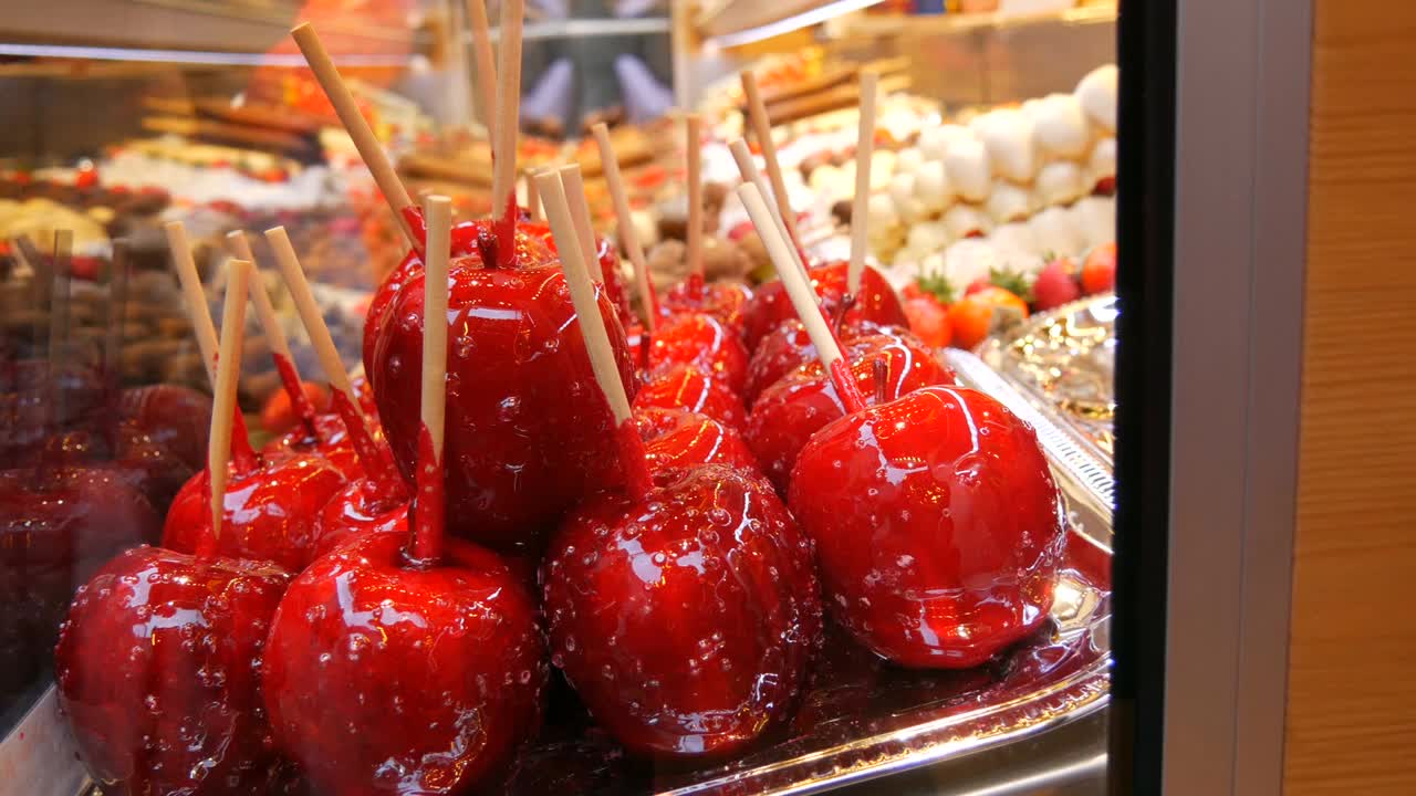 各种水果串在木串上，用牛奶、黑、白巧克力制成的焦糖釉。圣诞市场柜台上冰镇的苹果。街头食品视频素材