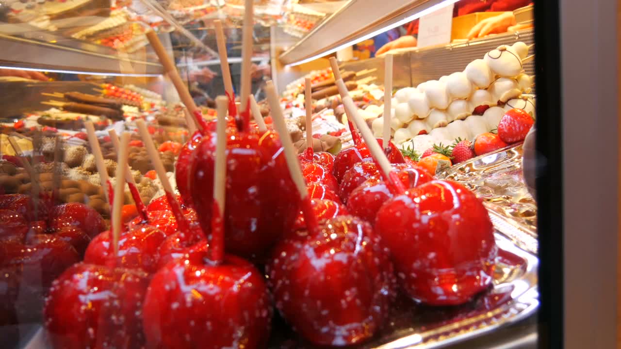 各种水果串在木串上，用牛奶、黑、白巧克力制成的焦糖釉。圣诞市场柜台上冰镇的苹果。街头食品视频素材