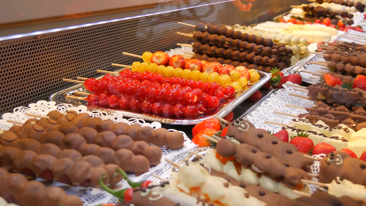 各种水果串在木串上，用牛奶、黑、白巧克力制成的焦糖釉。圣诞市场的柜台上摆放着葡萄、香蕉和糖衣草莓视频素材