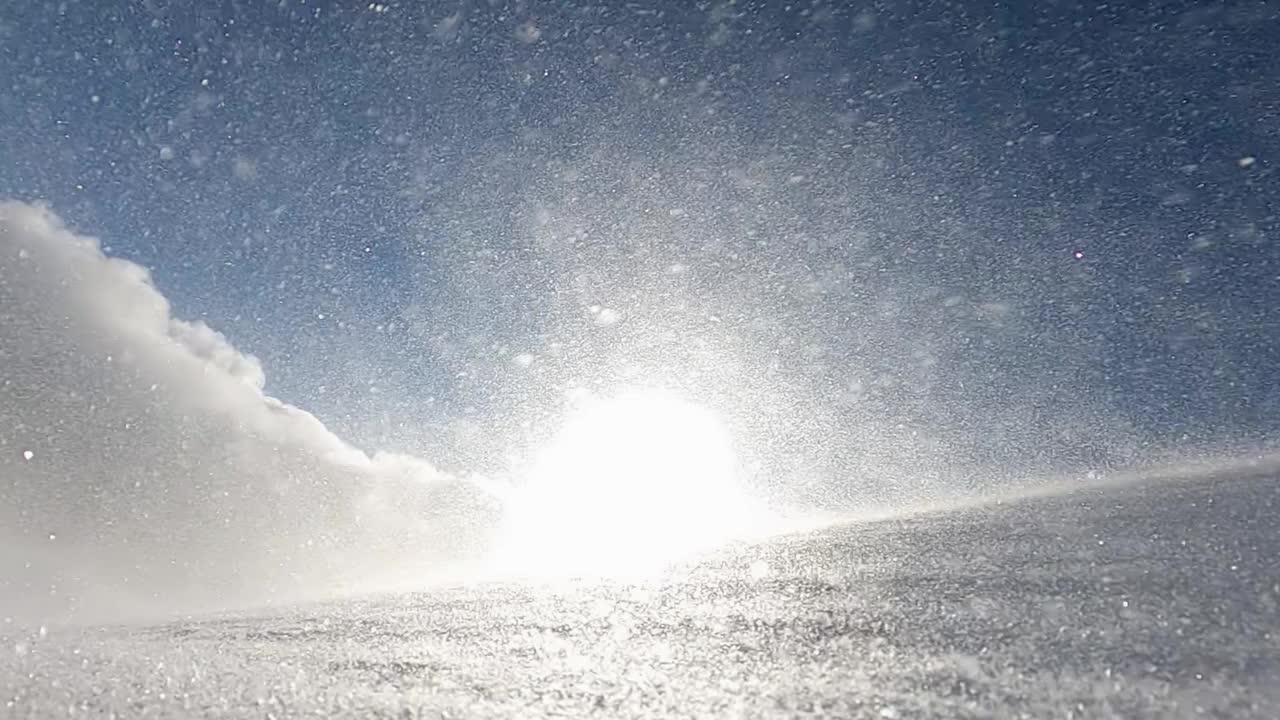 暴风雪的特写镜头，暴风雪和雪堆在山坡上，在寒冷的冬天早晨，阳光照耀着。慢动作视频素材