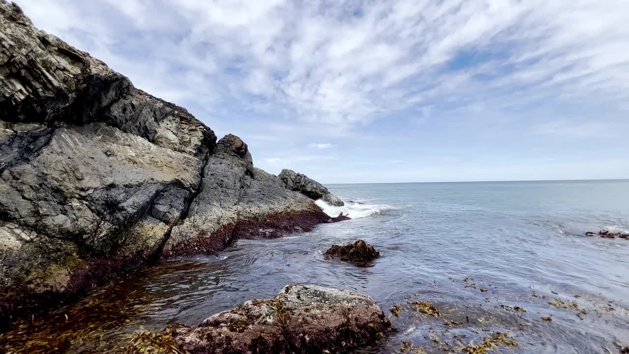 一个多岩石的岬角被海浪击中，海水沿着海岸打转。视频素材