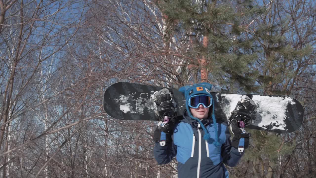 一名滑雪者拿着滑雪板爬过森林，到达坡顶视频素材