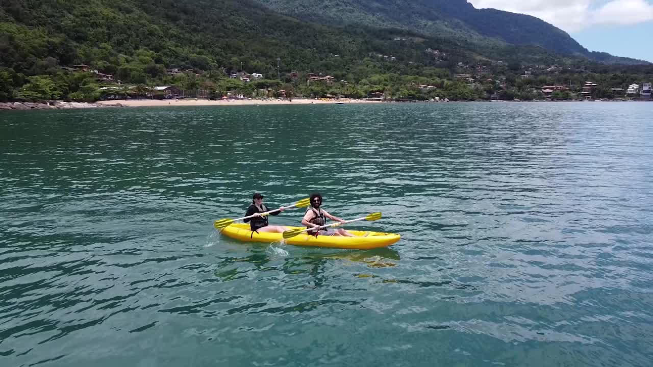 一对夫妇在海边划着黄色皮艇度假，享受着这一刻视频素材