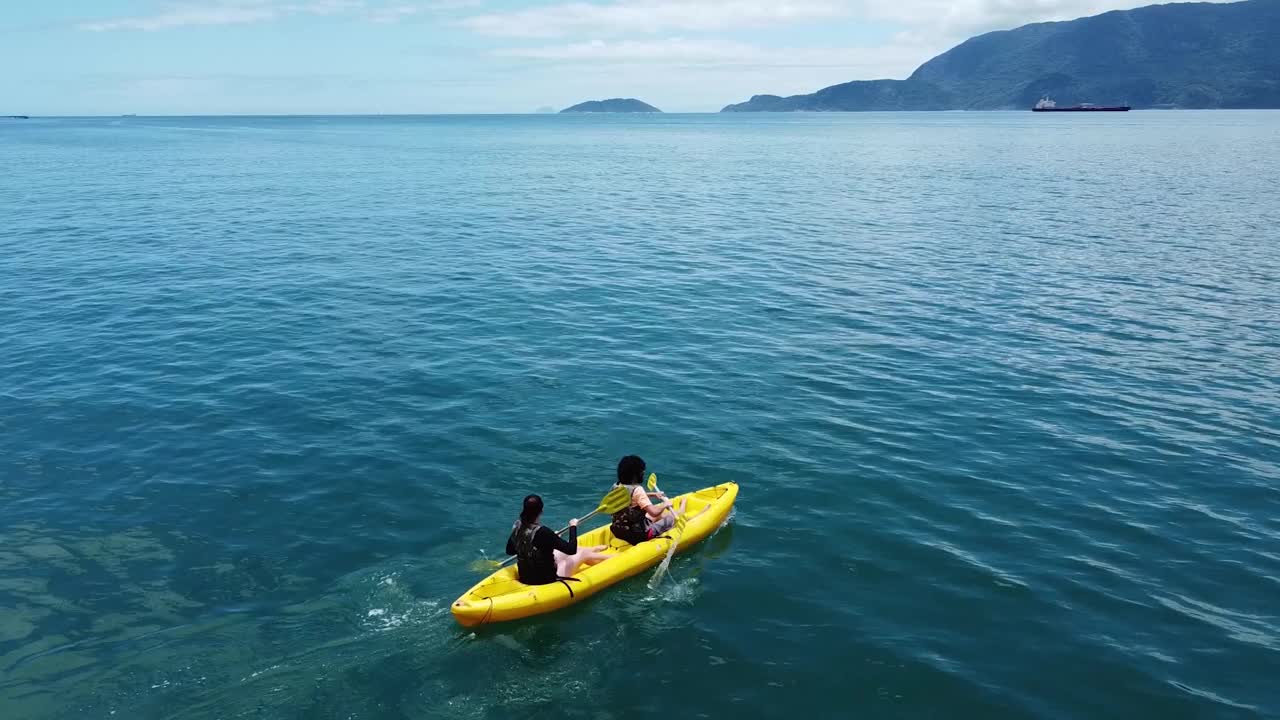 无人机拍摄的一对夫妇在海洋中划着黄色皮艇视频素材