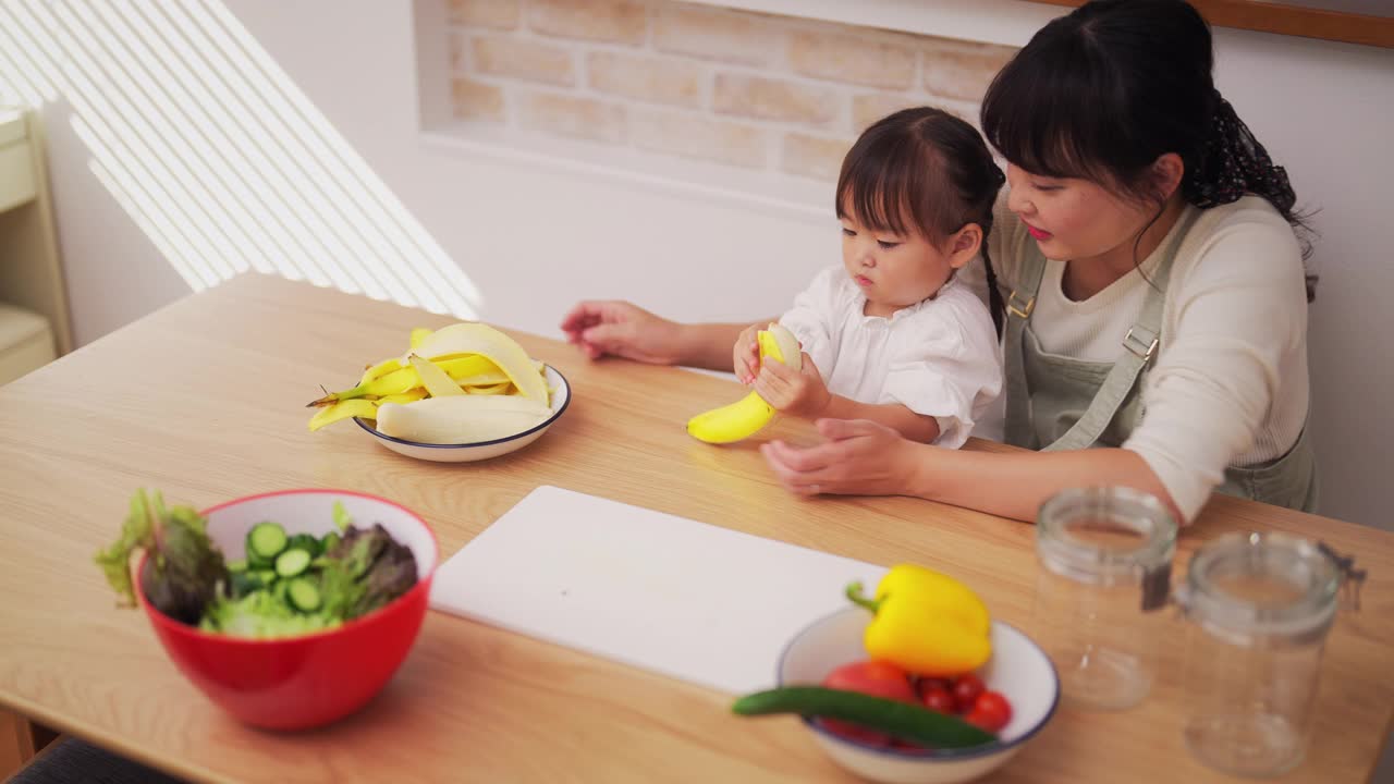 妈妈帮她的小女儿做冰沙，鼓励她健康饮食视频素材