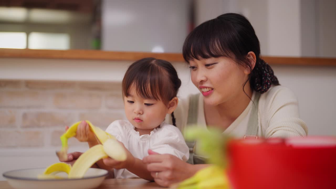 妈妈帮她的小女儿做冰沙，鼓励她健康饮食视频素材