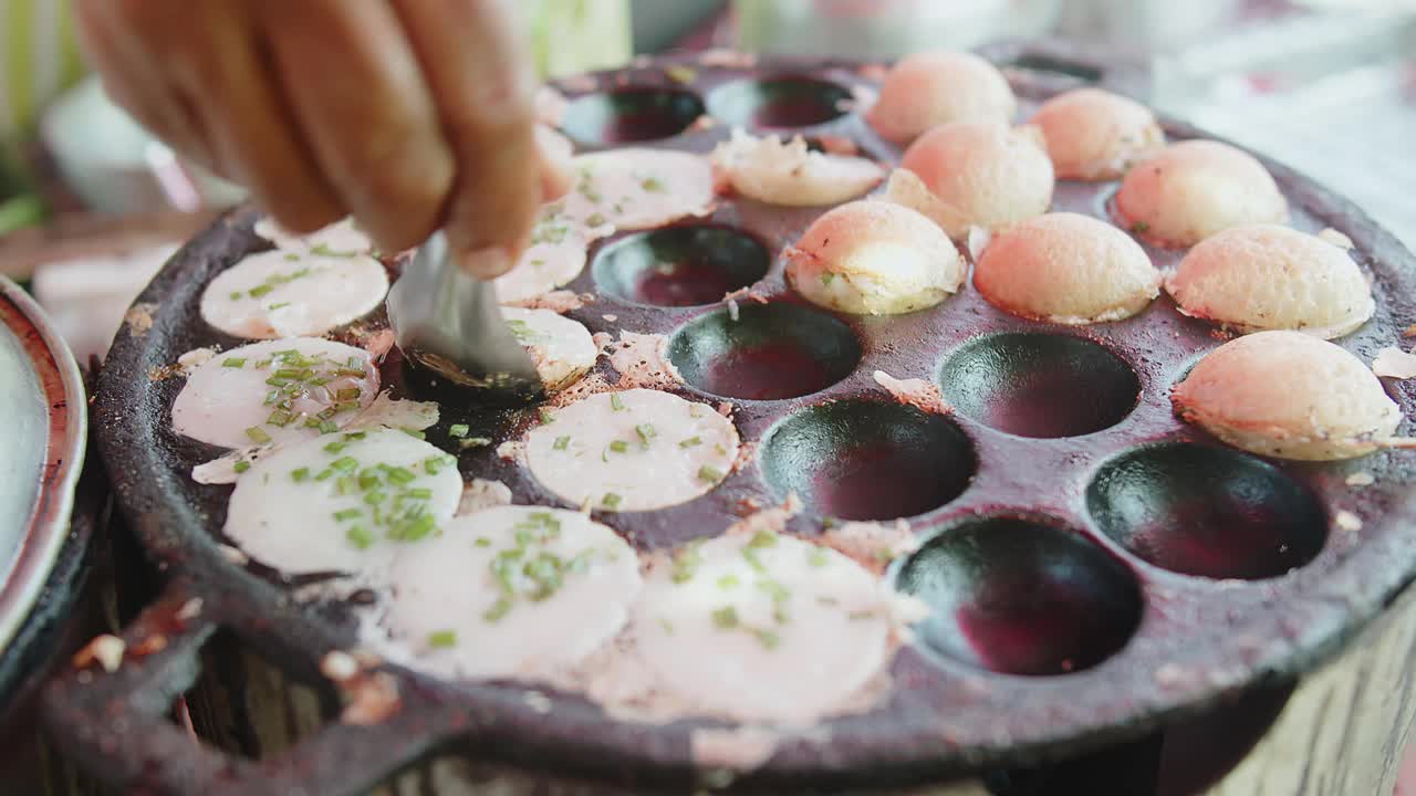 在热锅上手工烹饪传统的泰国街头小吃甜甜点Khanom Krok，椰奶煎饼，在上面放上糖和面粉视频素材