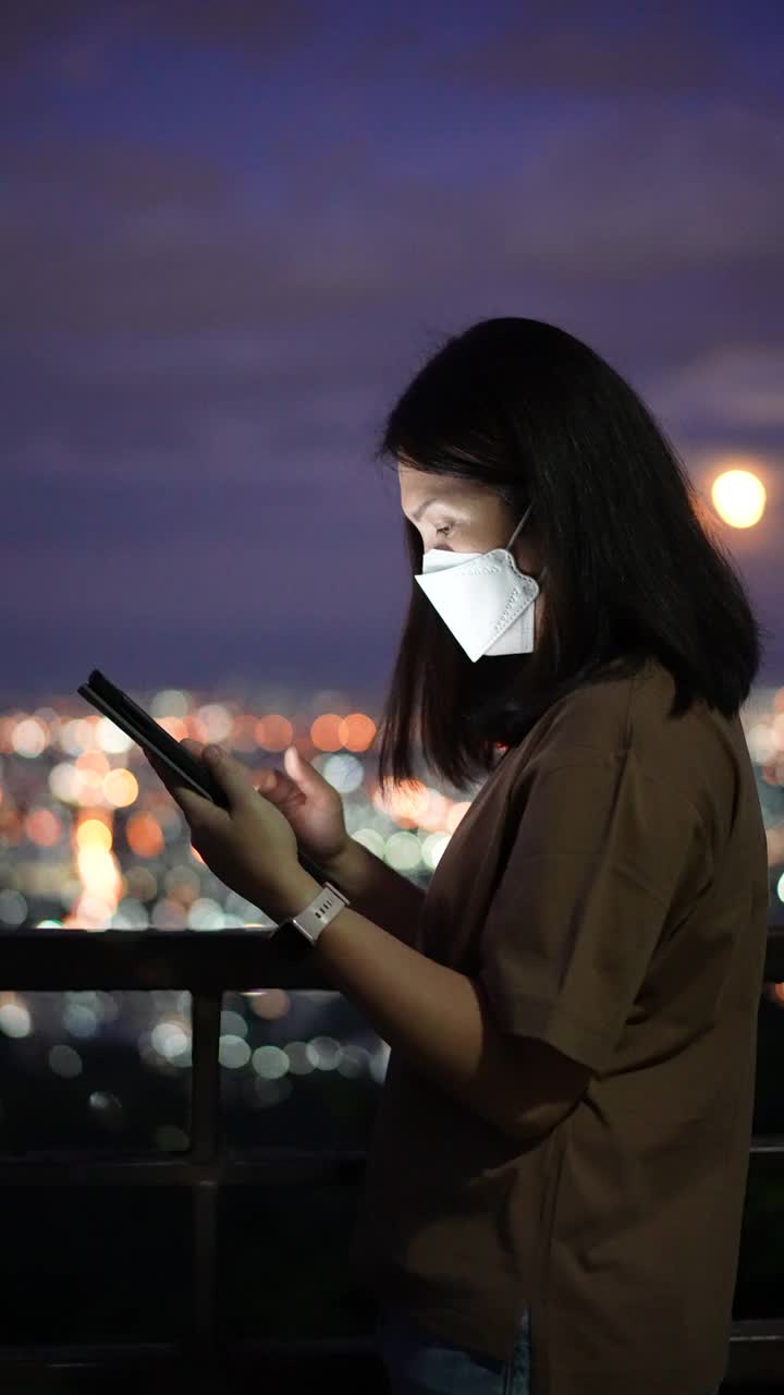 女人在夜里用手机用圆灯散景在城里视频素材