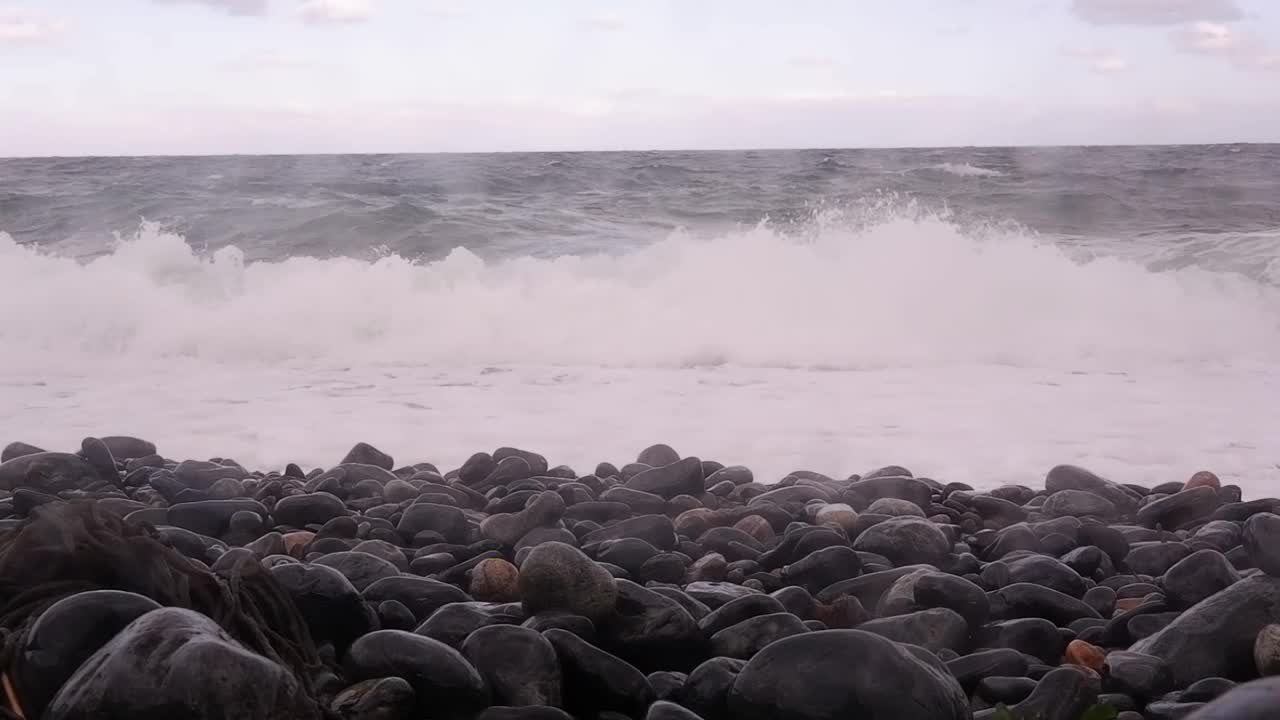 冬日里高耸的悬崖山峦间石质海滩的景色。视频下载