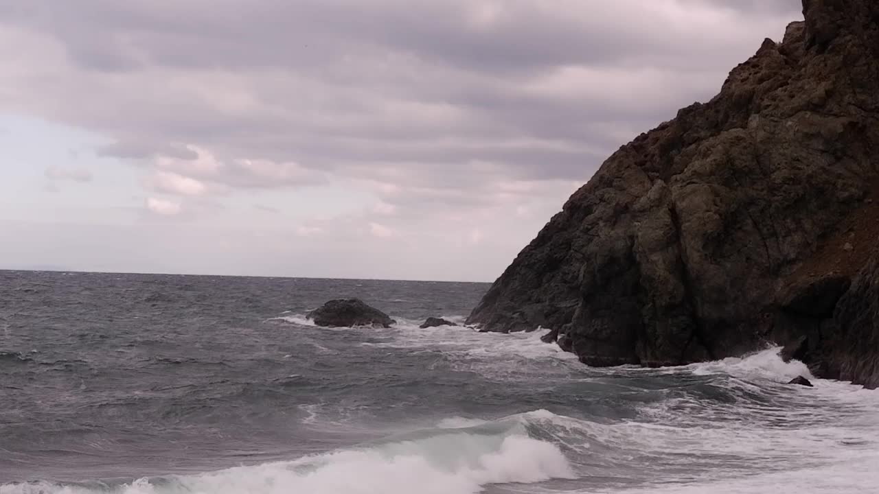 冬日里高耸的悬崖山峦间石质海滩的景色。视频下载