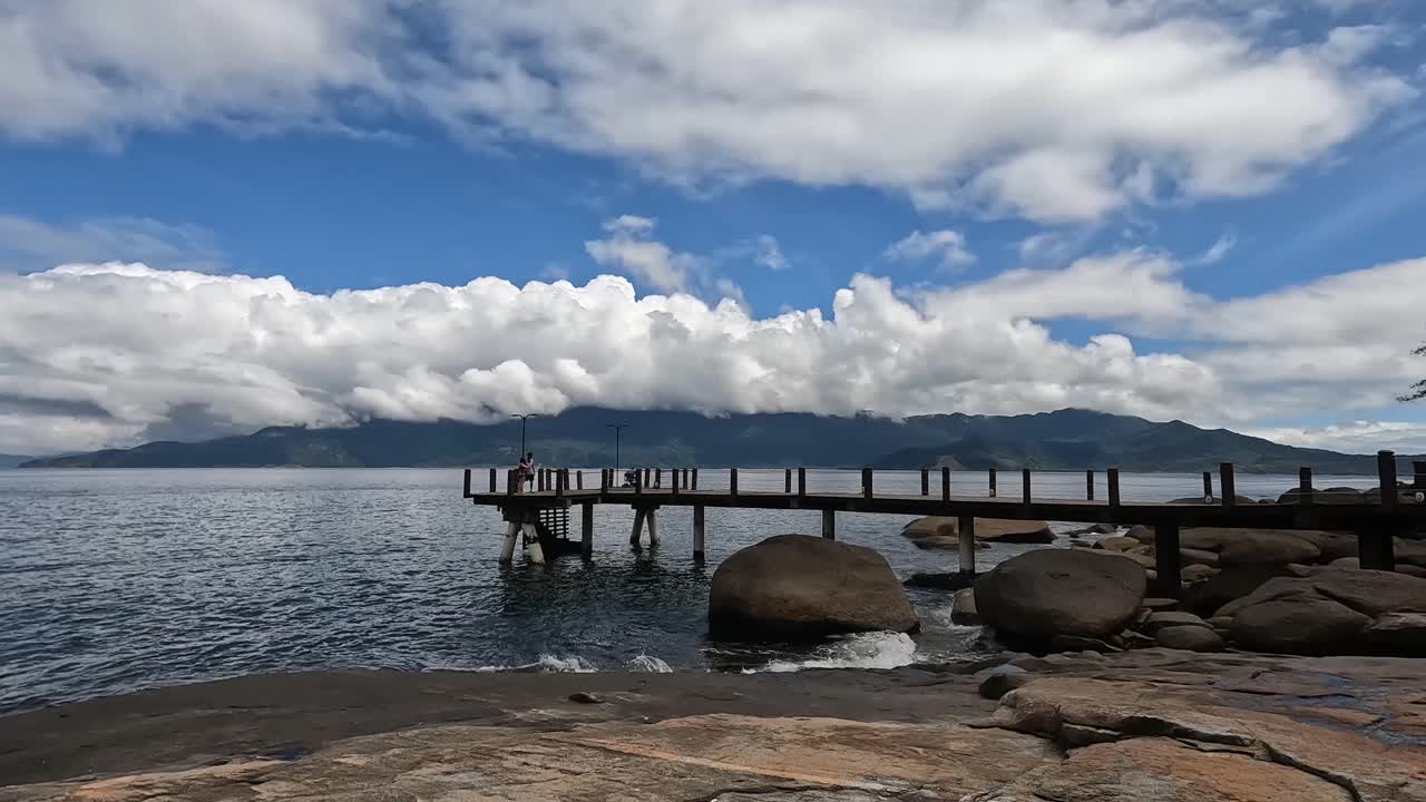 阳光明媚的日子在海岸线附近的一个大码头附近流逝。视频素材