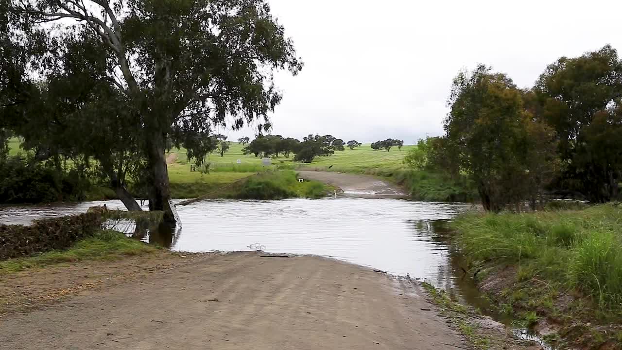 一条土路流过乡村土路上的一座桥，通向洪水泛滥的河流视频素材