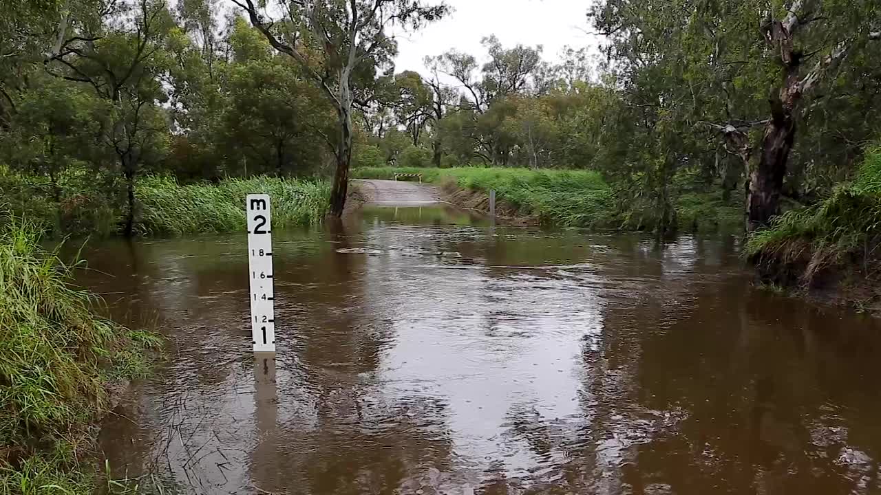 一条泛滥的河流从一座横跨乡村土路的桥上流过视频素材