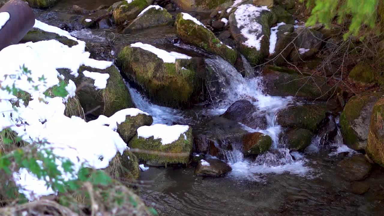 在喜马偕尔邦的马纳里，在冬天被白雪覆盖的岩石旁的水流的观点，印度。冬天的背景。在冬天，岩石旁流淌着小溪。视频素材