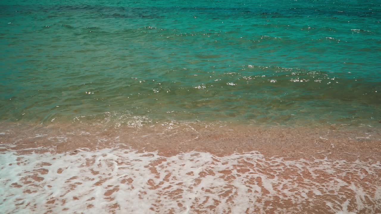 透明的绿色海浪平静地冲刷着沙滩视频素材