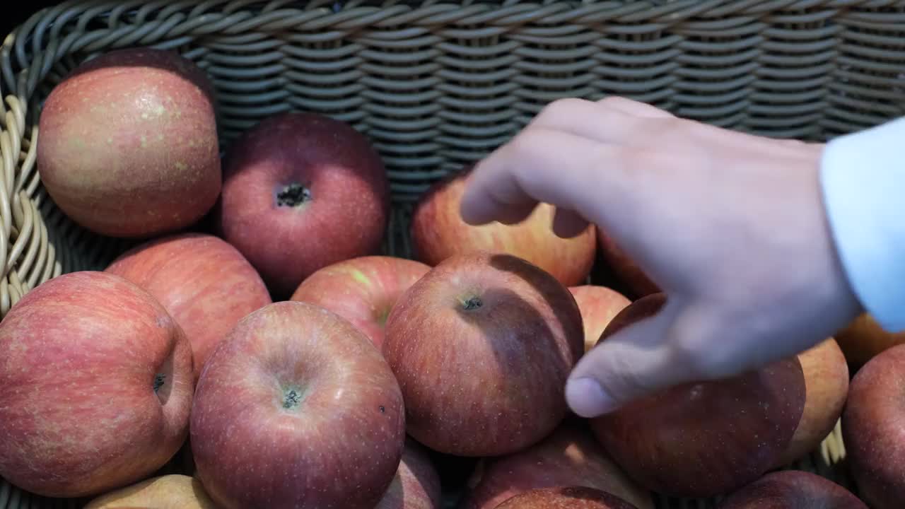 一个男人的手在超市摘苹果的特写。视频素材