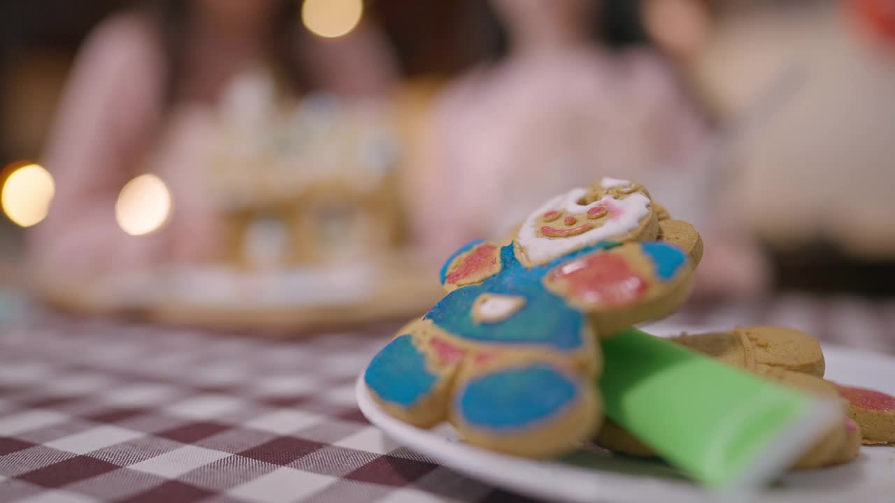 特写甜美可口的姜饼饼干在桌子上与模糊的女人和女孩在背景烹饪。美味的传统圣诞糕点在家里与母亲和女儿视频素材