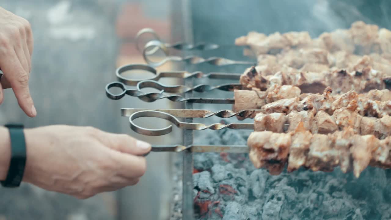 男人的手在火上转动着烤肉串。在烤架上煮肉。烧烤在自然界中。烤肉串在烟里。热的食物。户外野餐。视频素材