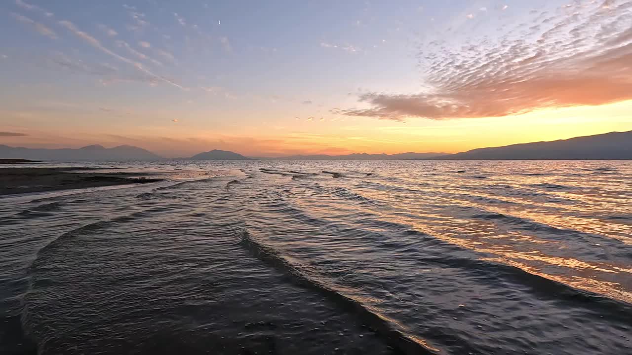 日落时，波浪翻滚着进入犹他湖的浅滩视频素材