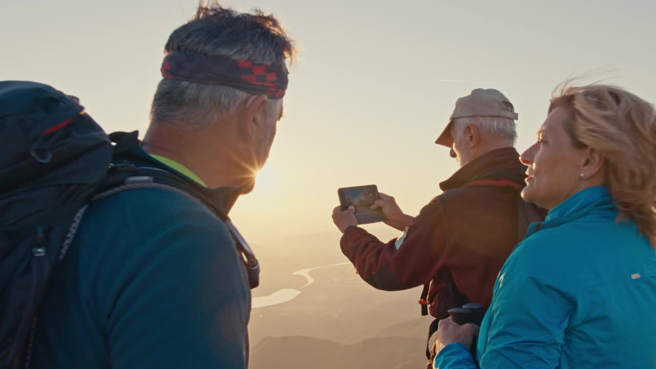 日落时分，SLO MO登山者用智能手机从山顶拍摄照片视频素材